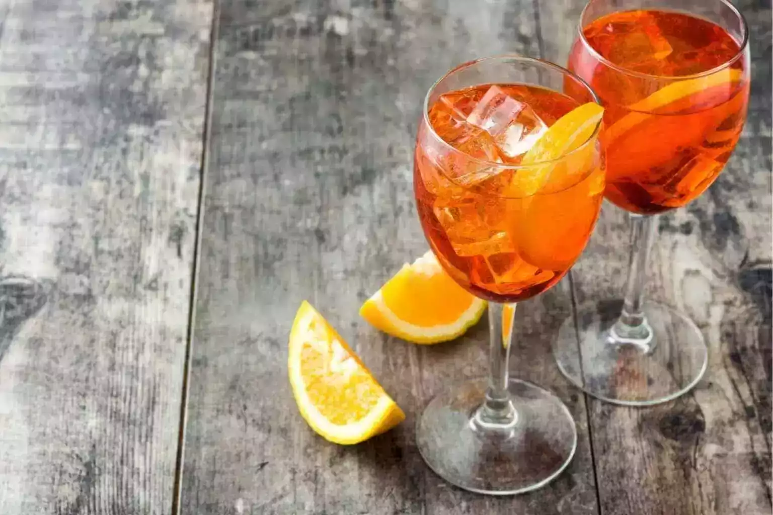 Due calici di spritz arancione su un tavolo di legno durante un aperitivo