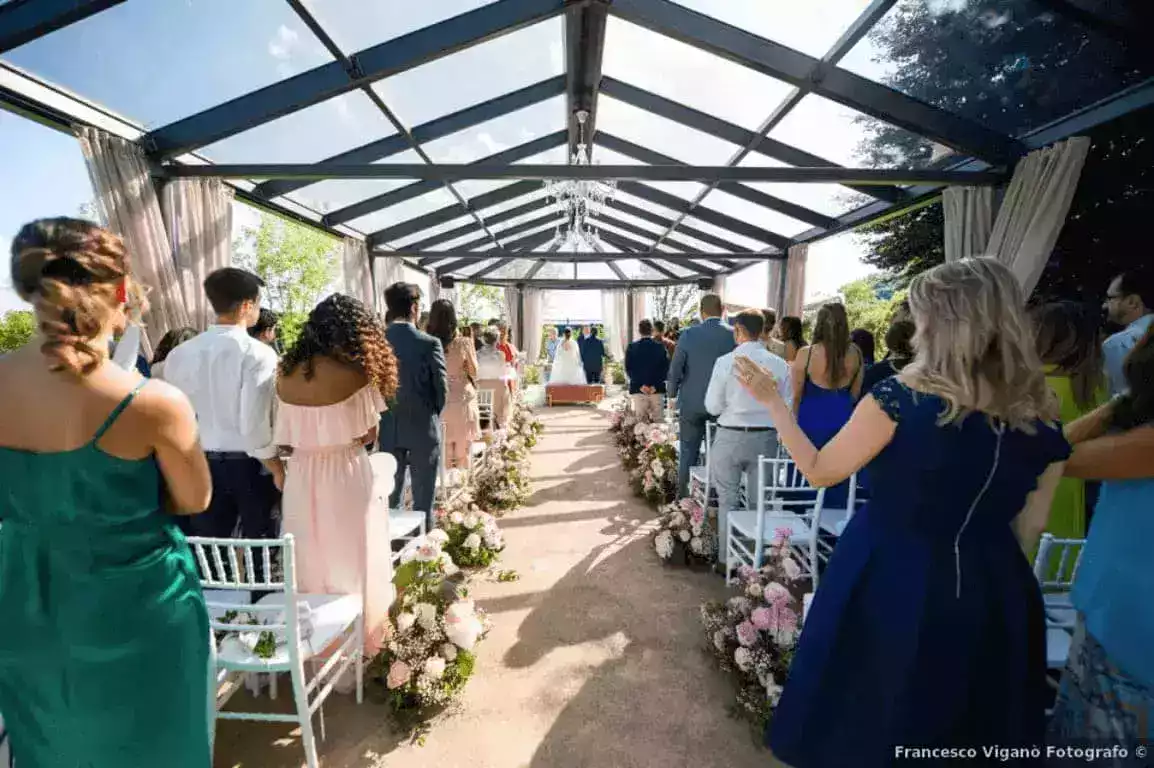 Cerimonia di matrimonio all'aperto con gli ospiti lungo il corridoio di fiori