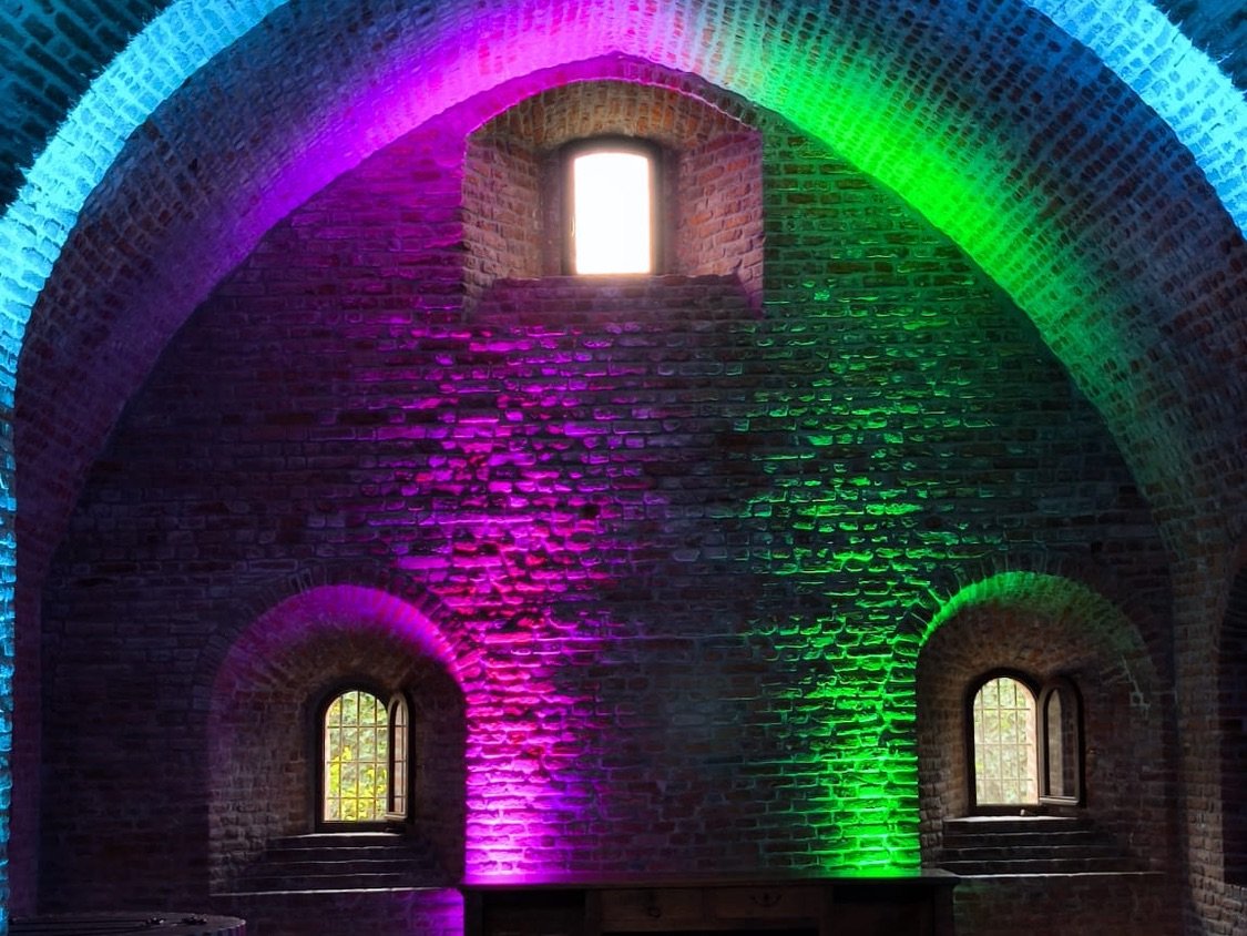 Antica sala in mattoni illuminata da luci colorate viola, verdi e azzurre: allestimento luci di MACO DJ per eventi a Bergamo